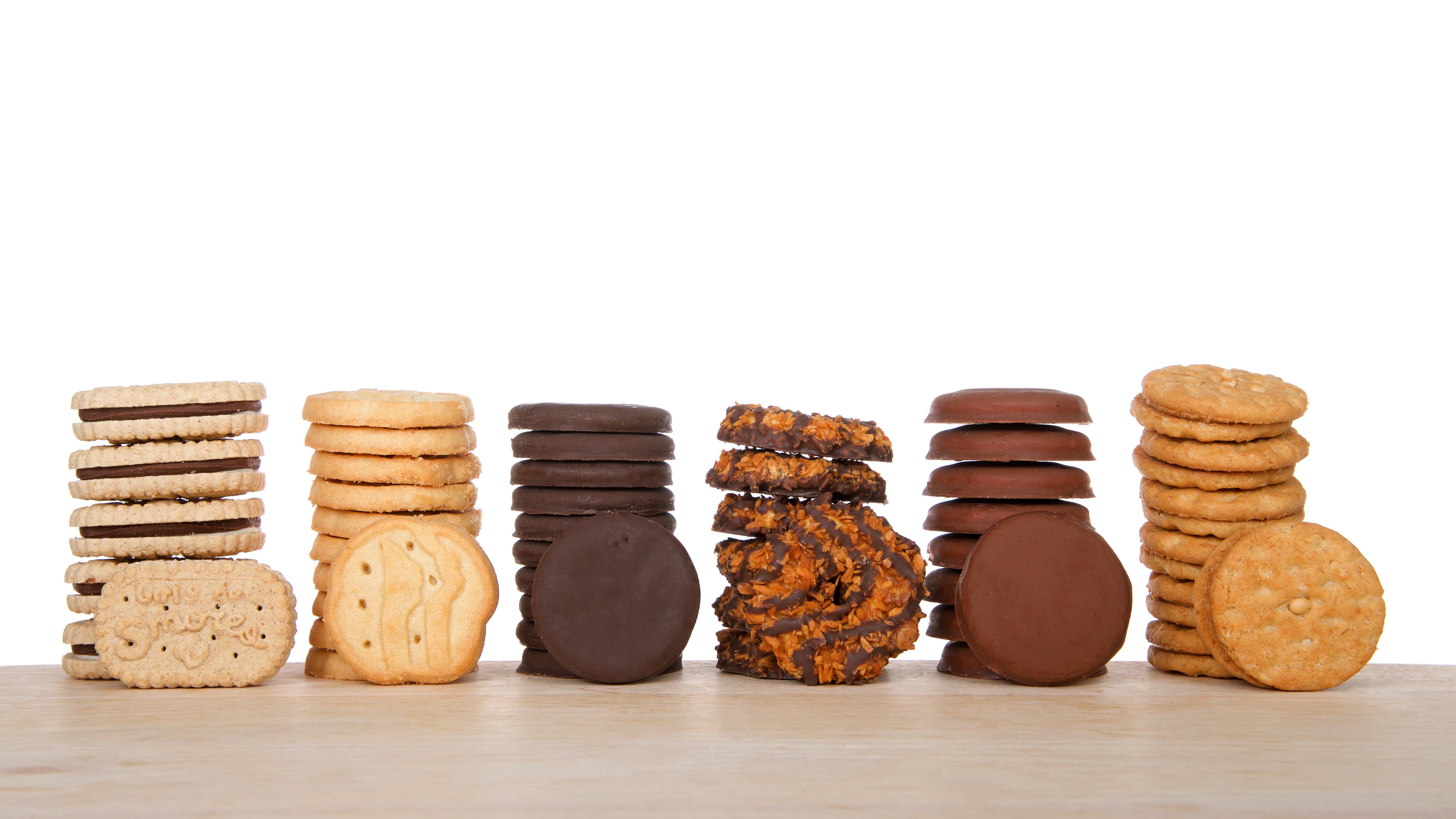 Stacks of popular Girl Scout cookies, Available annually during Girl Scout cookie sales, on a wood table with white background.