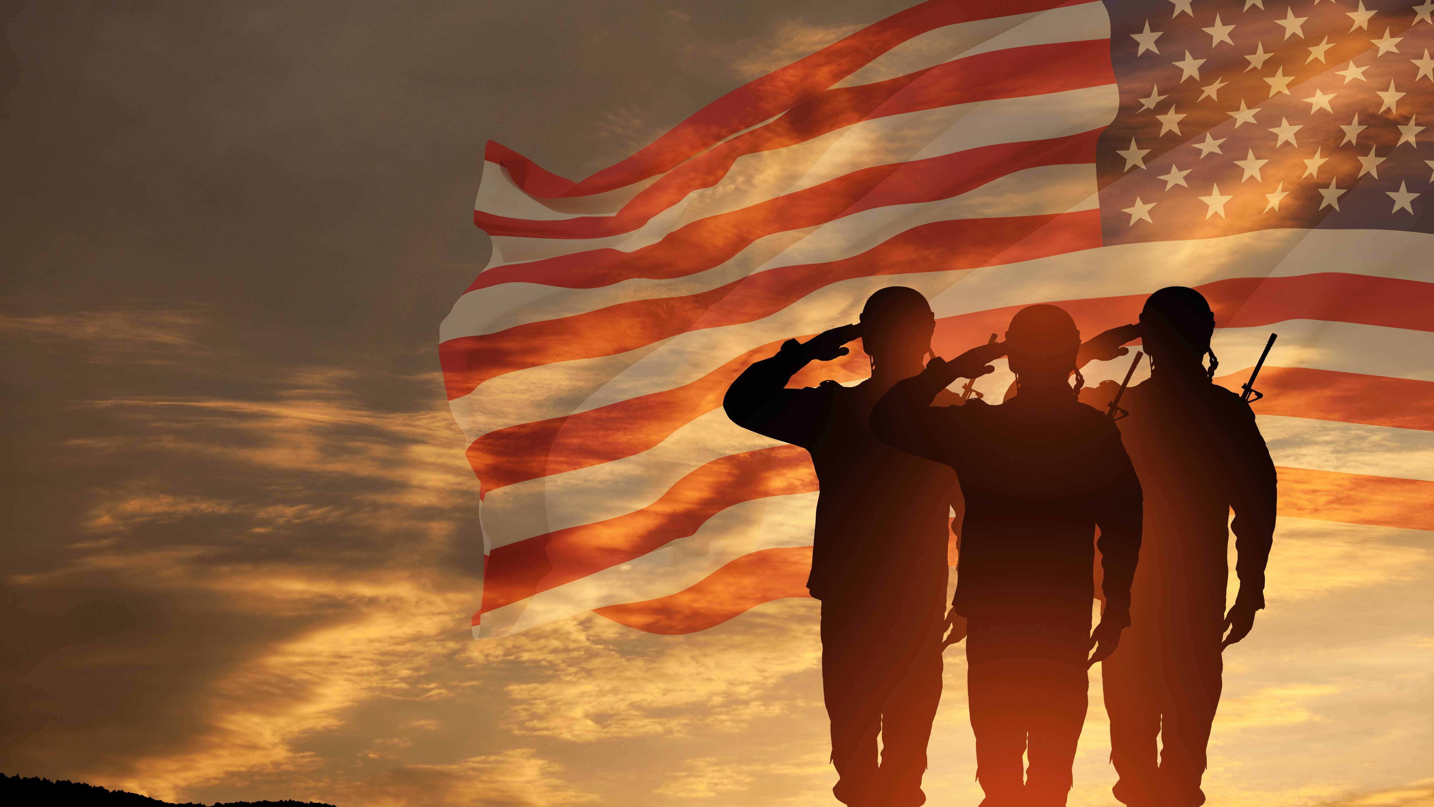 USA army soldiers saluting on a background of sunset or sunrise and USA flag.
