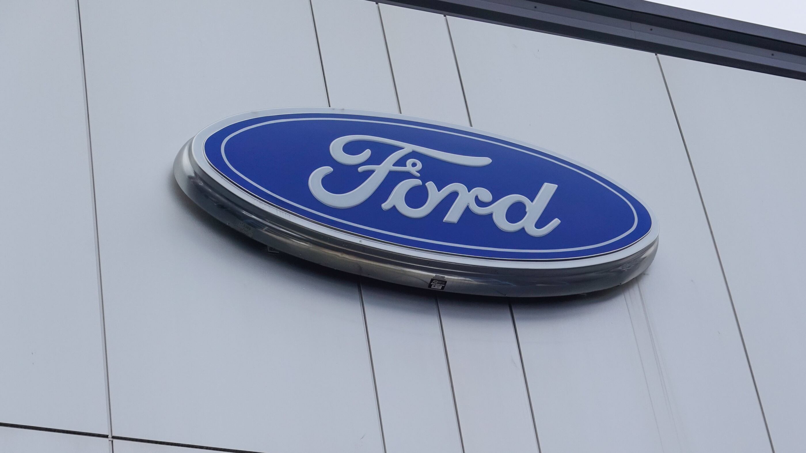 The Ford Motor Company logo as seen on the facade of a car dealership. Ford's headquarters are in Dearborn, Michigan